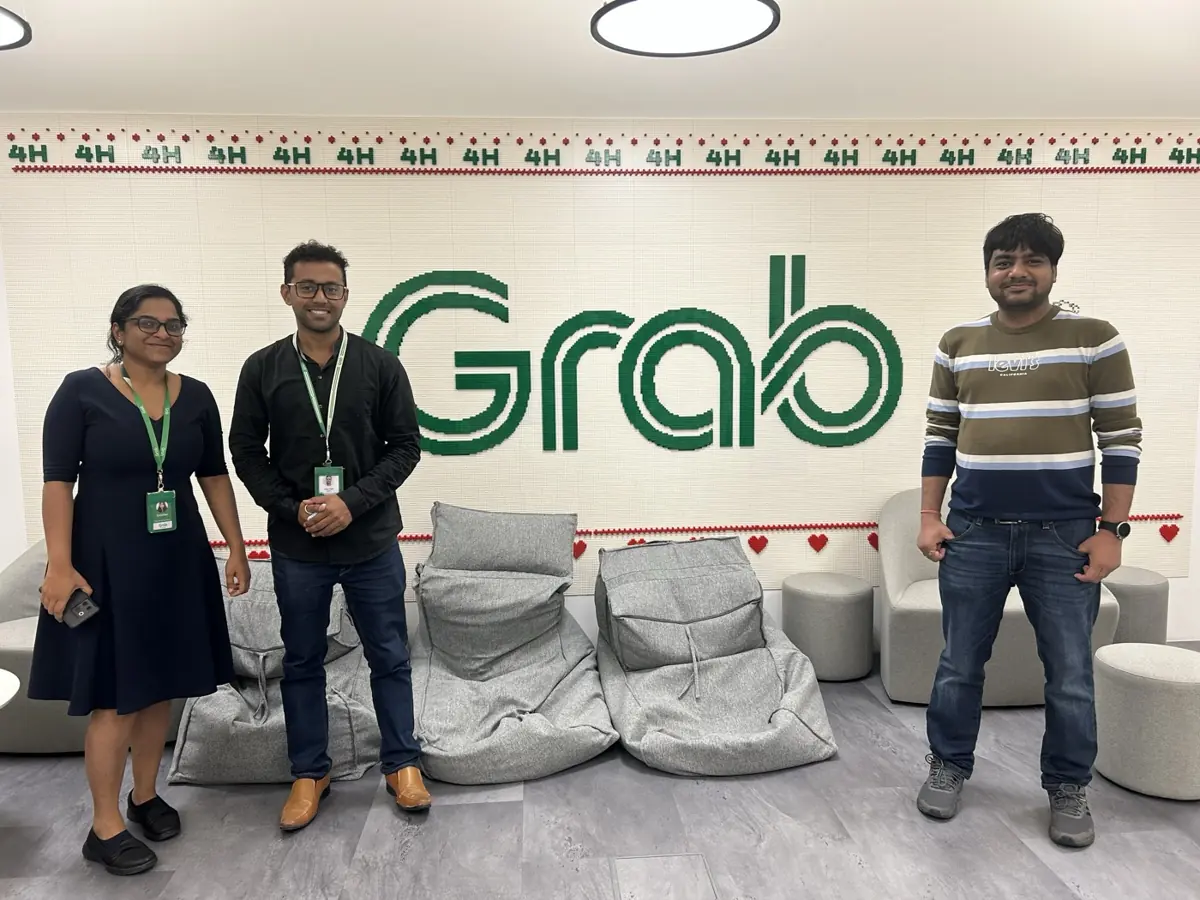 Three colleagues in front of the Grab wall